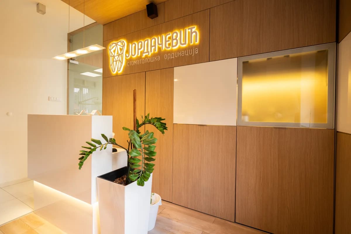 The entrance: reception desk and the illuminated practice sign on a wood-panelled wall